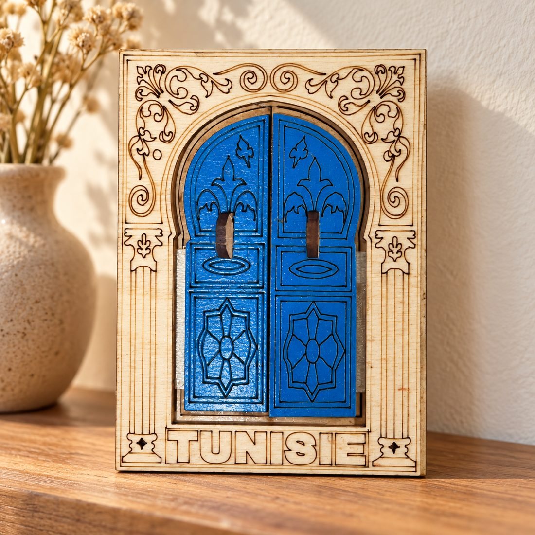 Cadre porte bleue « Tunisie » posé sur un buffet